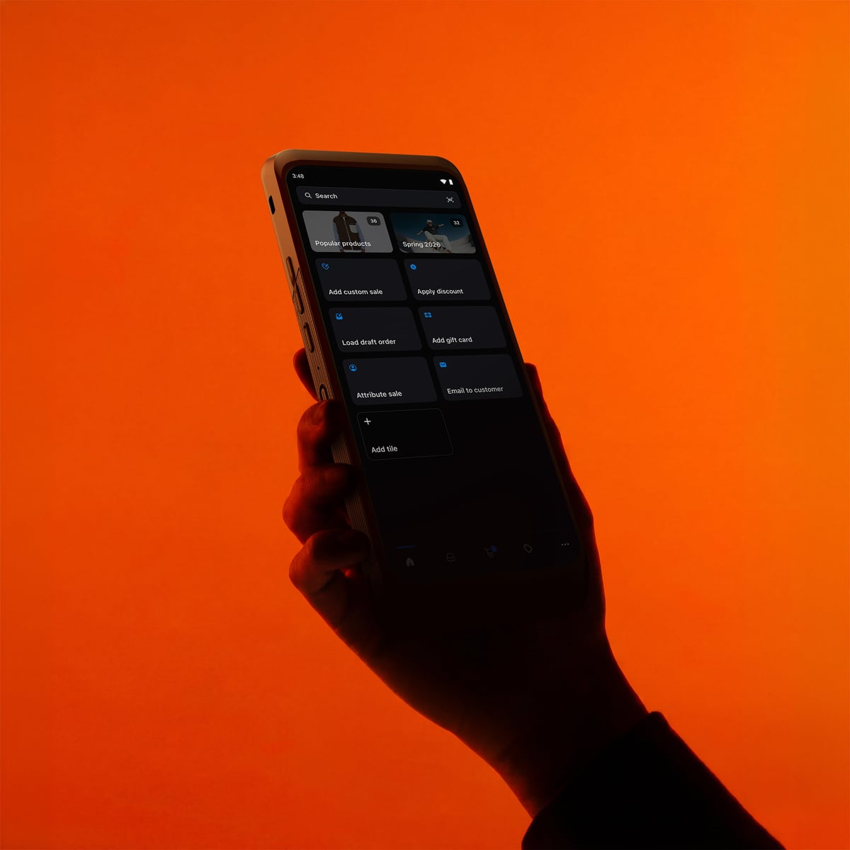 A hand holding a Shopify POS handheld device against an orange background