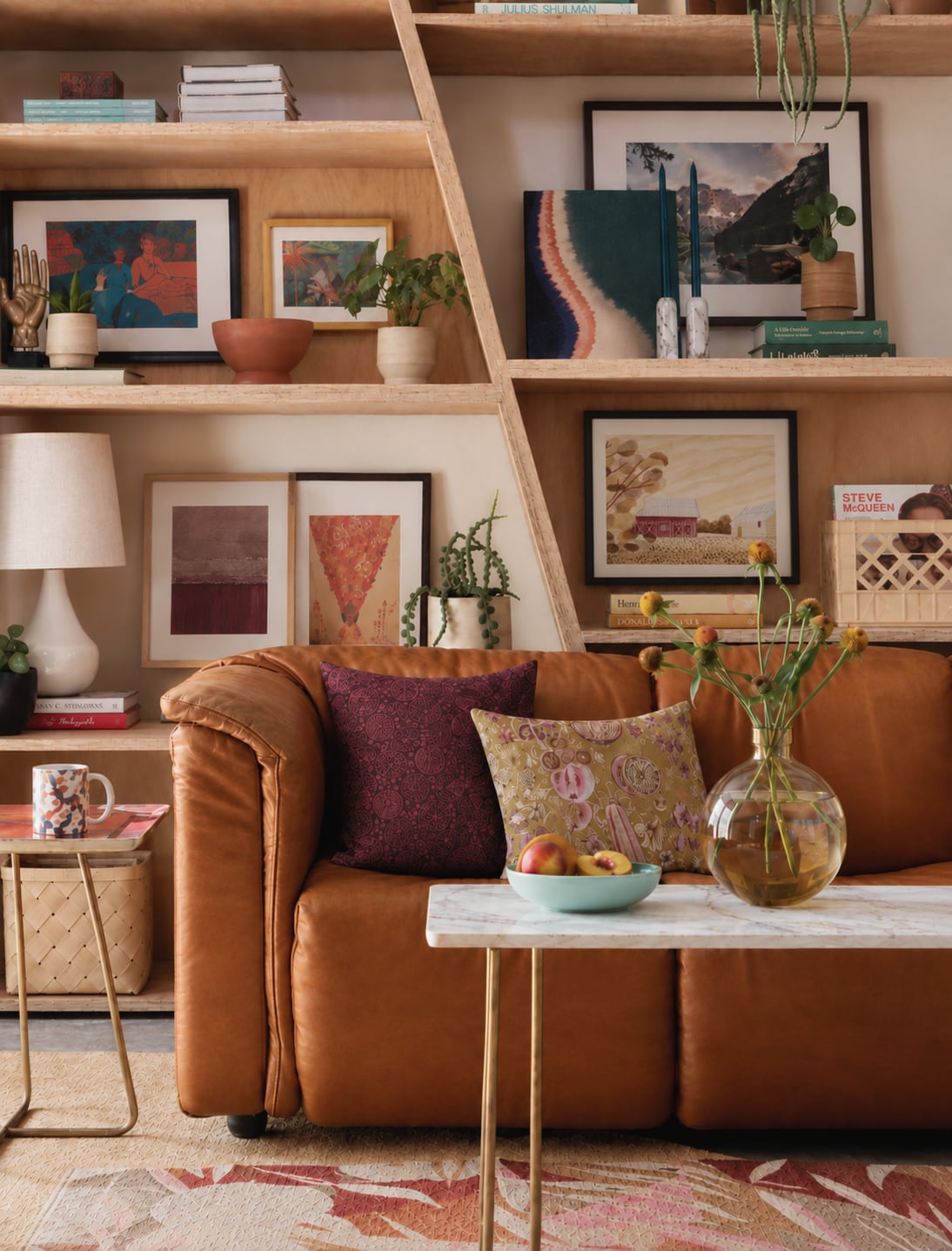 Framed artwork, colorful cushions and an amber sofa in a layered living room